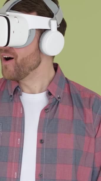 Un hombre que usa gafas de realidad virtual selecciona un menú 3D para el aprendizaje en línea. Simulador de juego digital. Vídeo vertical - Imágenes, Vídeo