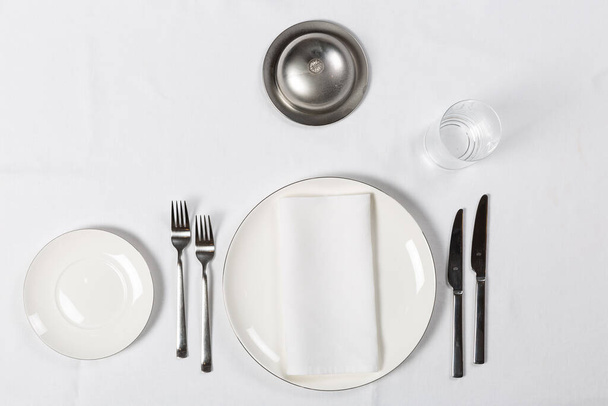Diverse opstellingen met bord, vork, mes op witte tafel - Foto, afbeelding