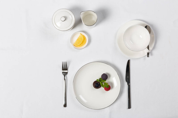 Various setup servings with plate, fork, knife on white table - Photo, Image