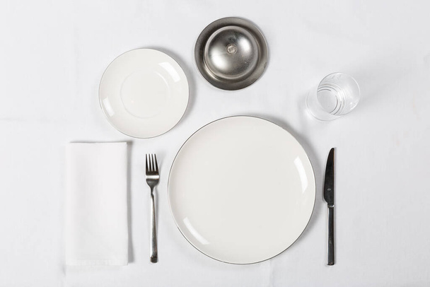 Varias porciones de configuración con plato, tenedor, cuchillo en la mesa blanca - Foto, Imagen