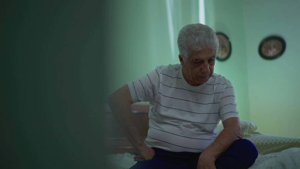 Ülő idős férfi küzd a befelé forduló gondolatok, aggódott kifejezése mély elmélkedés az ágy mellett - Fotó, kép