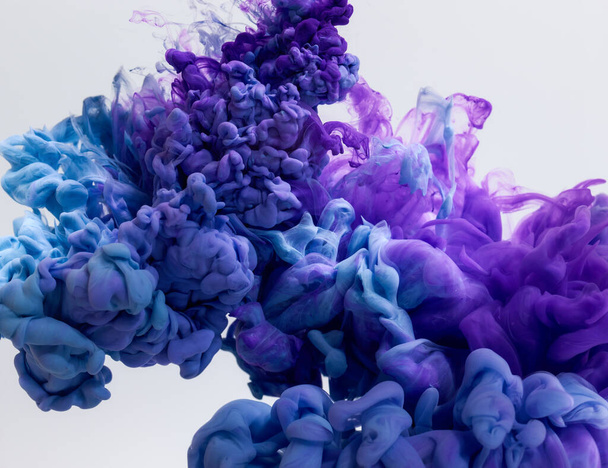 Plusk niebieskich i fioletowych farb w wodzie na szarym tle - Zdjęcie, obraz