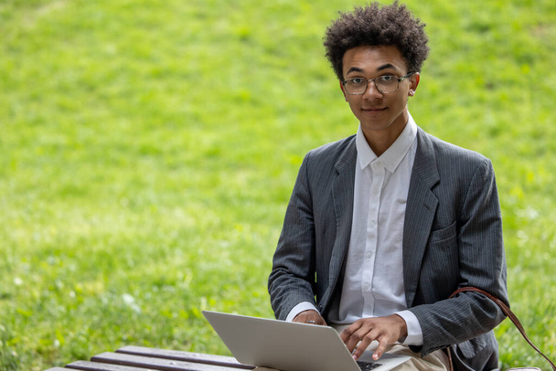 Digital nomad. Curly-haired young digital nomad working in the park - Foto, Imagen