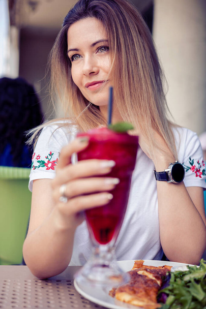 mulher desfrutando de um vibrante smoothie de baga vermelha em um cafee - Foto, Imagem