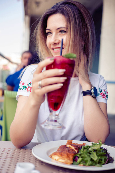 nő élvezi a vibráló piros bogyó smoothie a cafee - Fotó, kép