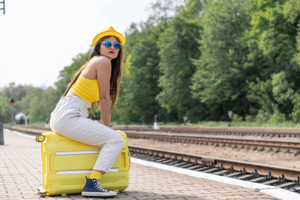 A stunning start to the journey: a girl in bright yellow looks preparing for adventures abroad. A young woman in spectacular glasses and bright stylish outfits goes on her dreamy journey. High quality - Photo, Image