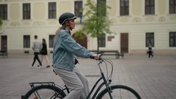 Blond lachende vrouw met beschermende helm, alleen op straat fietsend. Fijne toerist rijfiets. Reizen, fietsverhuur, zomerconcept - Video