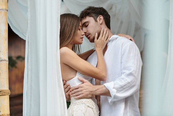 Нежная пара перед поцелуем, красивый мужчина обнимает женщину возле белого тюля частного павильона - Фото, изображение