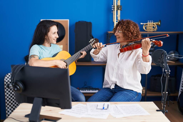 Two women musicians playing classical guitar and violin at music studio - Foto, Bild