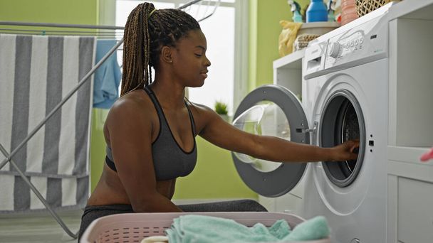 African american woman washing clothes at laundry room - Photo, Image