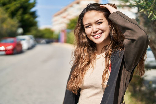 Fiatal gyönyörű spanyol nő mosolyog magabiztos áll a parkban - Fotó, kép