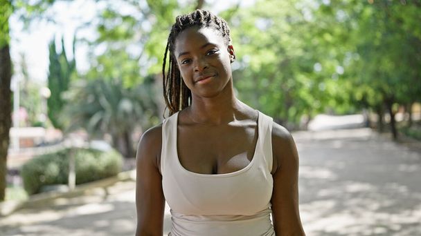Afrykańska amerykanka uśmiecha się pewnie stojąc w parku - Zdjęcie, obraz