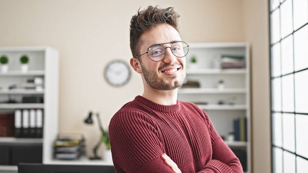 Young hispanic man business worker smiling confident standing with arms crossed gesture at office - Photo, image