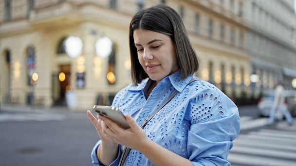 Молода красива іспаномовна жінка посміхається щасливим використанням смартфона на вулицях Відня - Фото, зображення