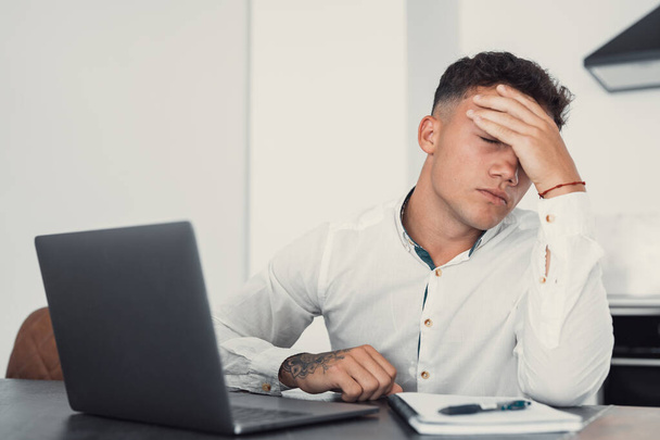 Benadrukt moe man in pijn hebben sterke verschrikkelijke hoofdpijn aanval na computer laptop vermoeid uitgeput man lijdt aan chronische migraine masseren van de tempels te ontlasten hoofdpijn spanning - Foto, afbeelding