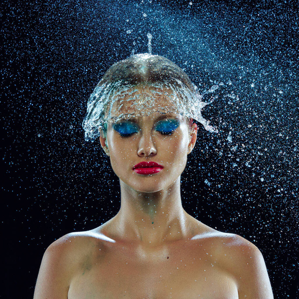 Portrait of beautiful wet young girls face. Drops of water running on her face with bright and colorful makeup over black background. Concept of beauty, fashion, art, halth, skin care. Ad. - Photo, Image