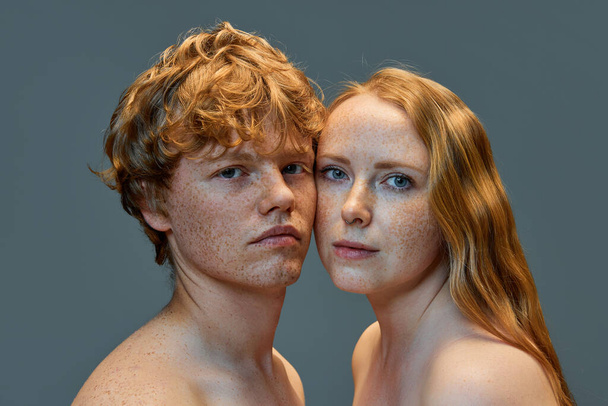 Portrait of beautiful red hair people on grey studio background. Woman and man with freckles and bare shoulders looking at camera. Concept of natural beauty, love, relationships, fashion. Ad - Photo, Image