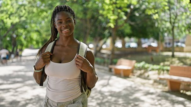 Afričanky americká žena turista nosí batoh s úsměvem v parku - Fotografie, Obrázek