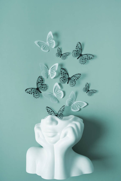 Une figurine d'une tête avec des papillons sur un fond coloré. Concept de santé mentale. - Photo, image