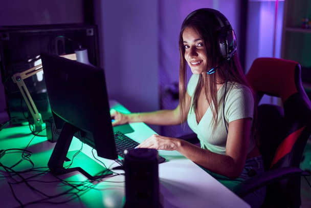 Young beautiful hispanic woman streamer playing video game using computer at gaming room - Fotoğraf, Görsel