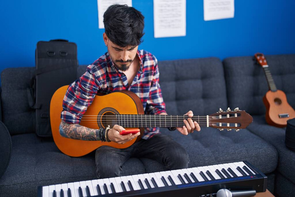Mladý hispánec muž umělec pomocí smartphone hrát na klasickou kytaru v hudebním studiu - Fotografie, Obrázek