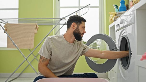 Giovane uomo ispanico lavare i vestiti in lavanderia - Foto, immagini