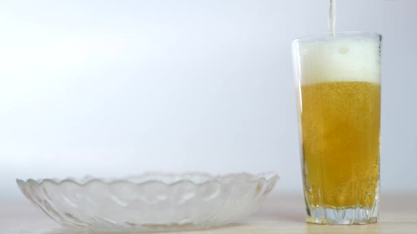 Bière mousseuse en verre close-up. Alcool bière dorée boisson dans une tasse. Tournage au ralenti de verser de la bière fraîche dans du verre sur fond blanc - Séquence, vidéo