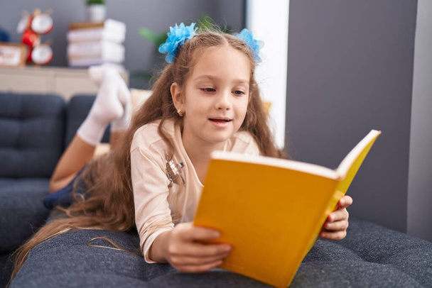 Adorável caucasiano menina leitura livro deitado no sofá em casa - Foto, Imagem