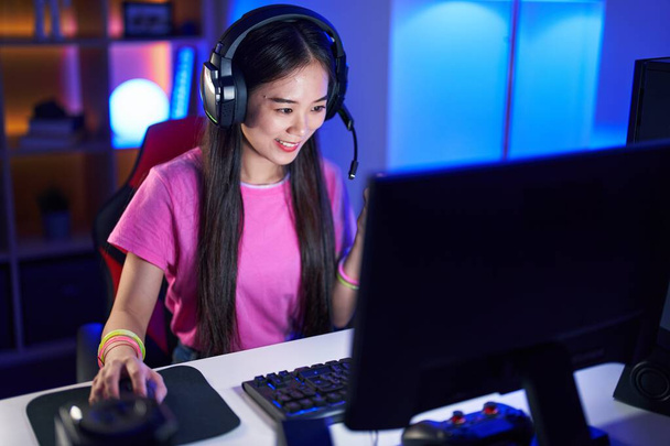 Νεαρή Κινέζα γυναίκα streamer παίζει βιντεοπαιχνίδι χρησιμοποιώντας υπολογιστή στην αίθουσα τυχερών παιχνιδιών - Φωτογραφία, εικόνα