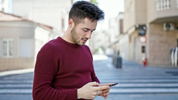 Νεαρός Ισπανός που χρησιμοποιεί smartphone με σοβαρή έκφραση στο δρόμο - Φωτογραφία, εικόνα