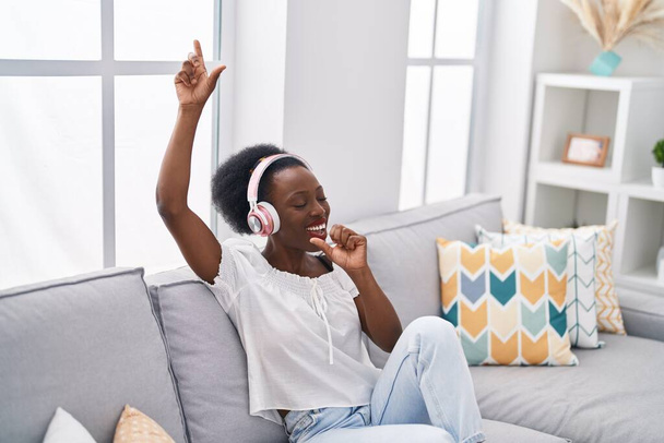 Donna afroamericana che ascolta musica che canta a casa - Foto, immagini