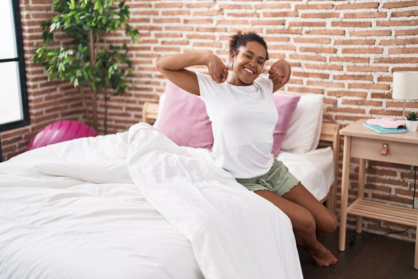 Африканская американка просыпается с протянутыми руками в спальне - Фото, изображение