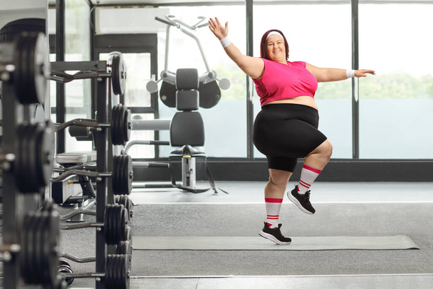 Cheerful plus size woman exercising at a gym and smiling at camera - 写真・画像