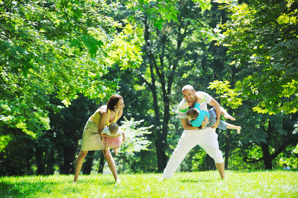 Happy νεαρό ζευγάρι με τα παιδιά τους να διασκεδάσουν στο πάρκο - Φωτογραφία, εικόνα