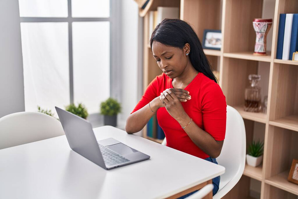 Молода афроамериканка використовує ноутбук, що страждає від болю в руці вдома - Фото, зображення