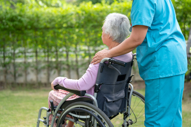 Lekarz pomoc i opieka azjatycki starszy kobieta pacjent siedzi na wózku inwalidzkim w parku w szpitalu pielęgniarskim oddział, zdrowe silnej koncepcji medycznej. - Zdjęcie, obraz