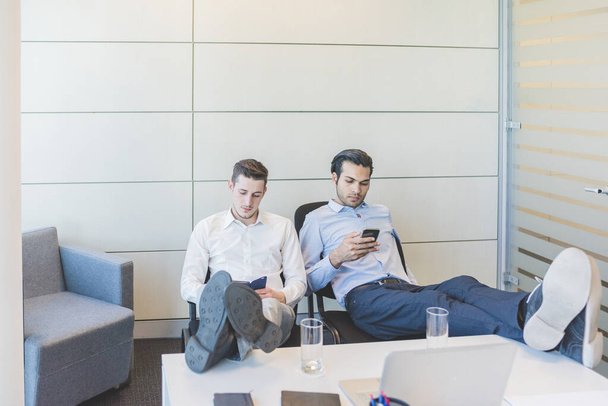 Kaksi monikansallista liikemiestä käyttää älypuhelinta - Valokuva, kuva