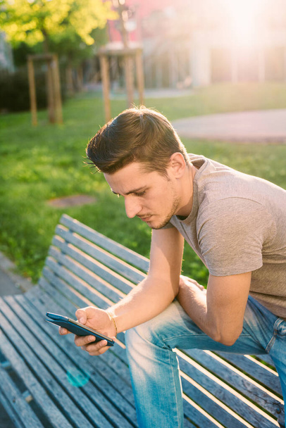 スマートフォン屋外を使用して若い男 - 写真・画像