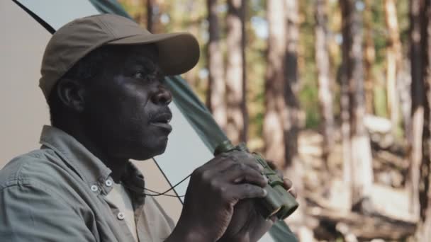 Oldalnézet közepes közelkép afro-amerikai vezető férfi turista, akik a távolságot távcsővel - Felvétel, videó