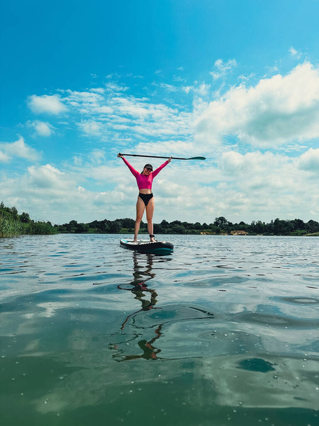 красива жінка, що стоїть на борту, тримає рівновагу охолодження на воді озера - Фото, зображення