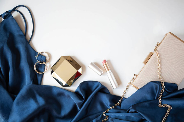 Les accessoires de couleur or pour femmes, le sac à main et la robe de cocktail en bleu sont sur un fond clair. Espace de copie. - Photo, image