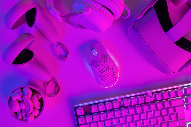 Overhead view van verschillende gadgets met marshmallows op paars gaming bureau - Foto, afbeelding
