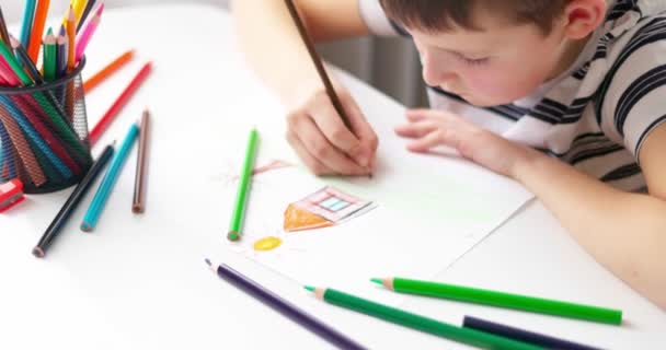 Roztomilý chlapec kreslí na kus papíru s barevnými tužkami doma nebo ve třídě. Učí se kreslit. Vzdělávací koncept. Vysoce kvalitní 4K záběry - Záběry, video