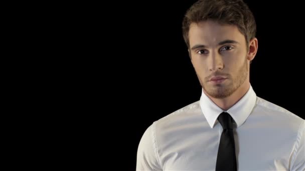 Serios caucasian man looking over his palm isolated against black background. Young man dressed in white shirt and black tie looking at copyspace. Stylish unshaven man turning his face to the raised - Footage, Video