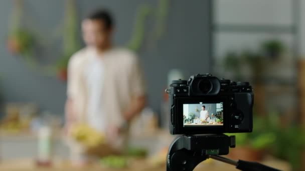 Selektivní zaostření záběru digitální fotoaparát stativ natáčení mužské jídlo blogger vaření v kuchyni při poskytování on-line kulinářské třídy nebo vytváření obsahu pro vlog - Záběry, video