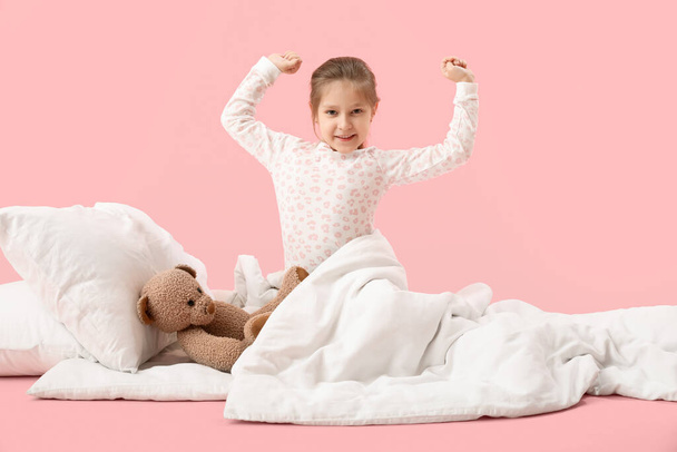 Little girl with soft blanket waking up on pink background - Photo, Image