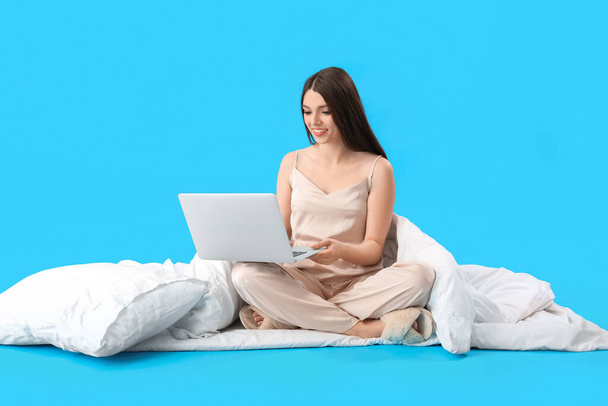 fiatal nő puha takaró segítségével laptop kék háttér - Fotó, kép