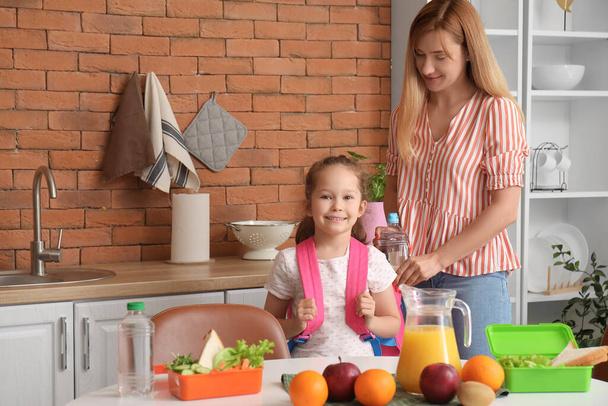 Mother packing school lunch for her little daughter in kitchen - Photo, Image