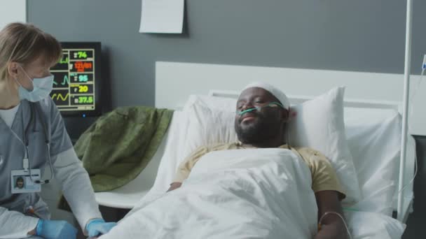 Une femme praticienne travaillant à l'hôpital militaire parle à un patient afro-américain pour le réconforter et le soutenir - Séquence, vidéo