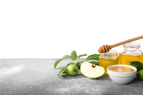 白い背景に対してテーブルの上に甘い蜂蜜と緑のリンゴが付いている瓶 - 写真・画像